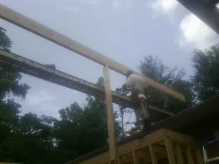 Carpenter setting a ridge beam over a new addition frame — Ice Dam Removal by Roofing Brothers in Sea Cliff