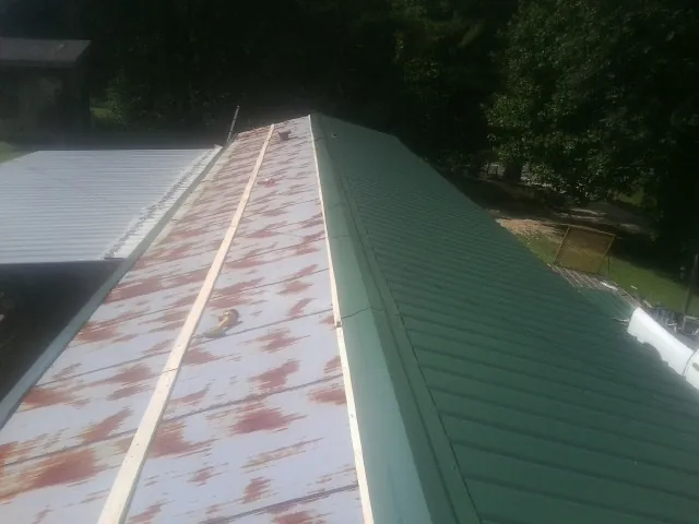 Old rusted panels beside newly installed green metal roofing — Wind Damage Roof Repair by Roofing Brothers in Sea Cliff
