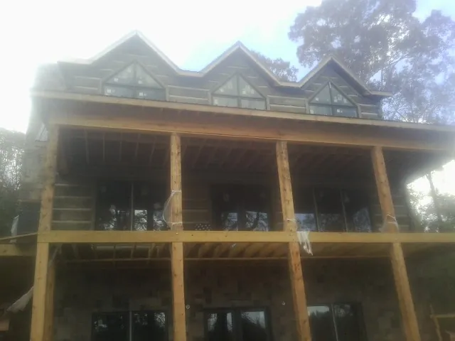 Dormers and porch framing on a large log home under construction — Roof Coating work by our crew in Sea Cliff