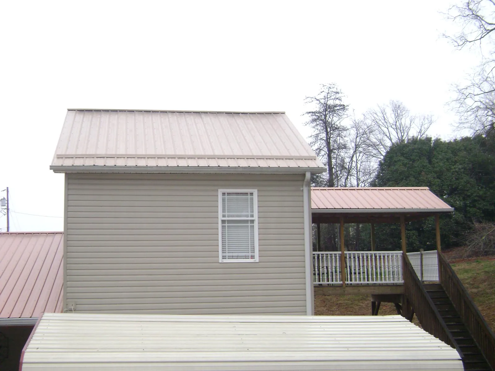 Tan metal roofs on a two story addition and attached porch, from a Roof Replacement job in Sea Cliff