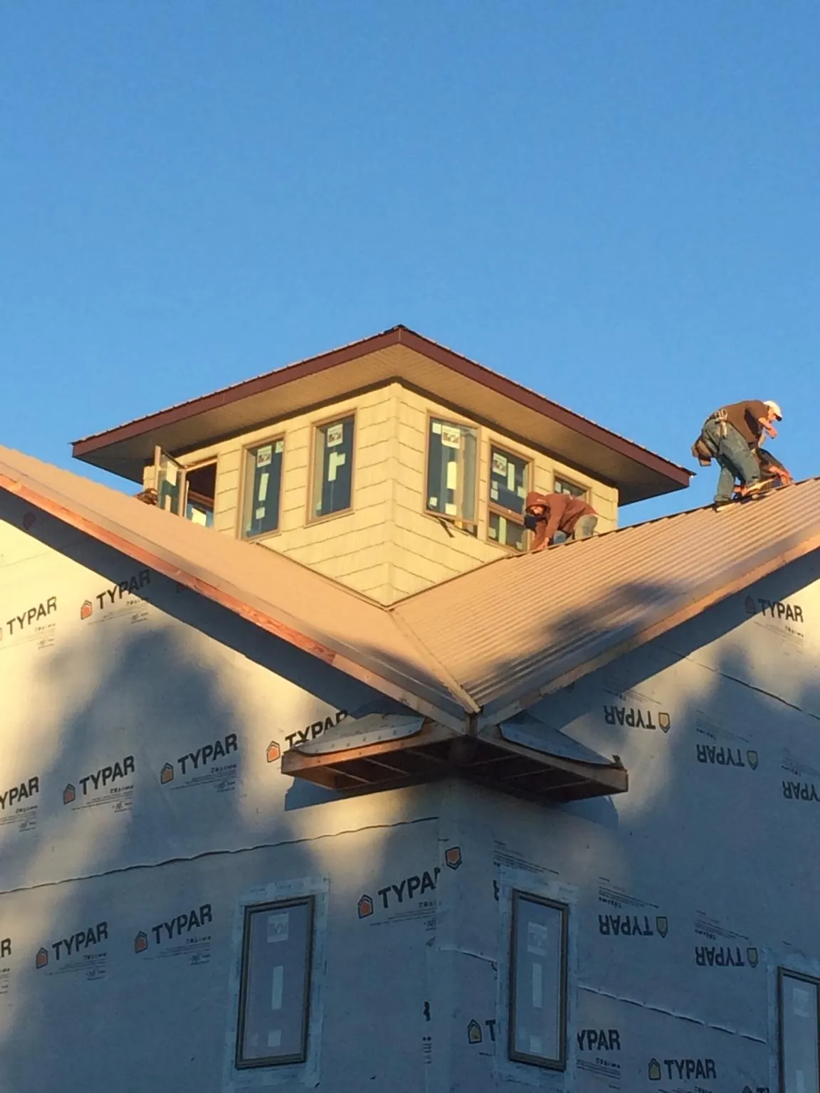 Roofers working around a rooftop cupola on a new metal roof at sunset — Roof Waterproofing in Sea Cliff by Roofing Brothers